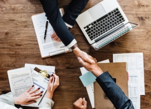 Two people shaking hands across desk